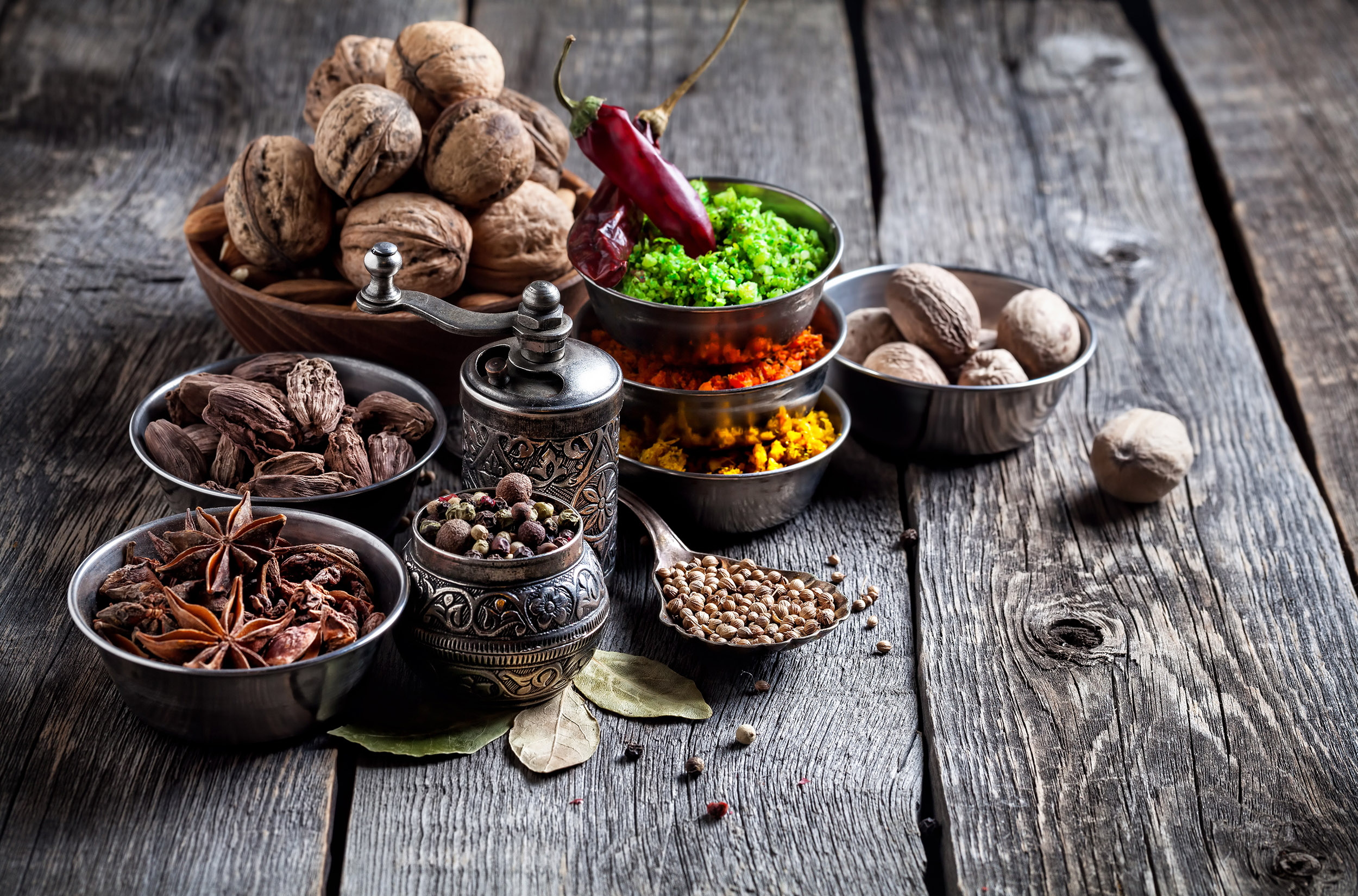 Spices, pepper grinder, spoon with seeds at grey wooden background
